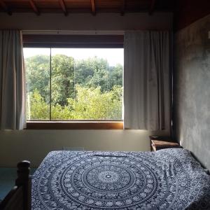 a bedroom with a bed with a large window at Pousada Recanto Devas in Cabo Frio