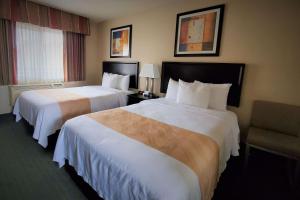 a hotel room with two beds and a chair at Quality Inn & Suites Anaheim at the Park in Anaheim
