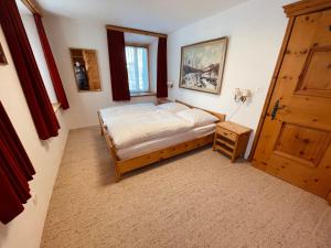 sypialnia z łóżkiem i drewnianymi drzwiami w obiekcie Chesa Coronella w mieście La Punt-Chamues-ch
