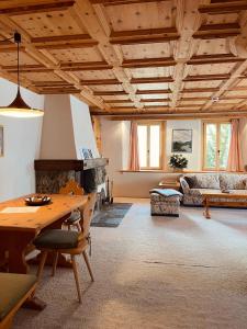 a living room with a table and a fireplace at Chesa Coronella in La Punt-Chamues-ch
