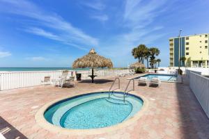 a swimming pool with a umbrella and chairs and the ocean at Sea Breeze 106 in St Pete Beach