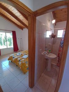 a bathroom with a bed and a sink and a shower at Cabañas Mérida Ruta 66 in El Hoyo