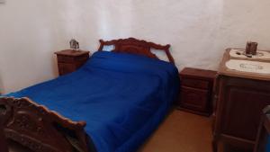 um quarto com uma cama azul e um lavatório em La Casa De La Gruta em Mina Clavero