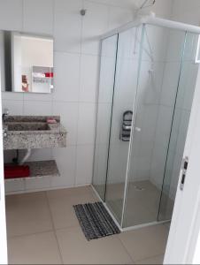 een badkamer met een douche en een glazen deur bij Apartamento à 300 mts da praia in Itapoa