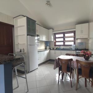cocina con mesa y nevera blanca en Casa de 2 Quartos na Praia da Joaquina, en Florianópolis