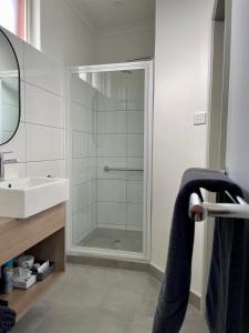 uma casa de banho com um chuveiro e um lavatório. em Tarra Motel em Yarram