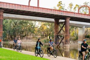 a group of people riding bikes on a path under a bridge at Mercure Port of Echuca in Echuca
