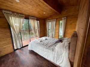 1 dormitorio con 1 cama en una habitación con ventanas en Casa en el Árbol Guatavita en Guatavita