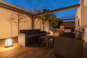 eine Terrasse mit einem Sofa und Stühlen auf einer Holzterrasse in der Unterkunft Bijou Suites AI PREMIUM in Osaka