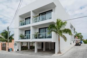 Un edificio blanco con una palmera delante. en Dreams Apartments 8. Loft a 9 minutos de la playa, en Isla Mujeres