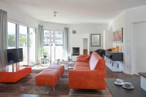 ein Wohnzimmer mit einem orangenen Sofa und einem TV in der Unterkunft Cara in Garmisch-Partenkirchen
