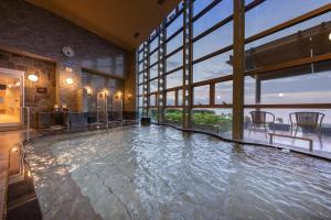 a swimming pool in a building with a large window at KAMENOI HOTEL Ako in Ako