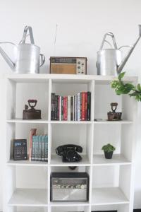 a white book shelf with books and pots on top at Bu Sepuh GuestHouse in Sangkanurip