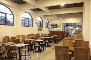 a restaurant with wooden tables and chairs and windows at Bu Sepuh GuestHouse in Sangkanurip