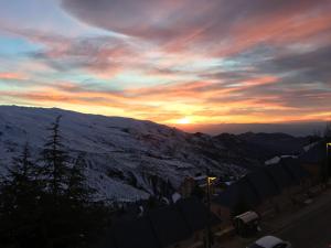 einen Sonnenuntergang über einem schneebedeckten Berg mit dem Himmel in der Unterkunft ALCAZABA ZONA MEDIA in Sierra Nevada