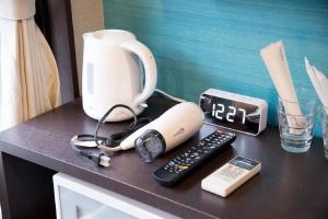 einen Schreibtisch mit einem Telefon, einer Kaffeemaschine und einem Wecker in der Unterkunft akihabara marutomo hotel in Tokio