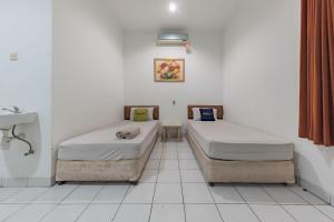 a room with two beds and a sink at Urbanview Hotel Pondok Kurnia Cijagra Bandung in Bandung