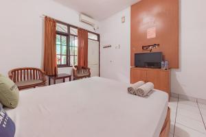 um quarto com uma grande cama branca e uma televisão em Urbanview Hotel Pondok Kurnia Cijagra Bandung em Bandung