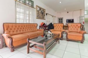 twee oranje leren banken en een salontafel in de woonkamer bij Urbanview Hotel Pondok Kurnia Cijagra Bandung in Bandung