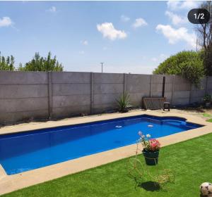 ein Schwimmbad in einem Garten neben einem Zaun in der Unterkunft Casa de totys en la Serena in La Serena