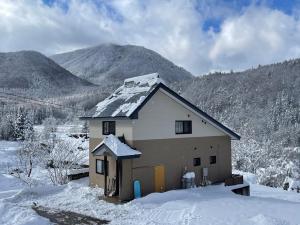 a house covered in snow with mountains in the background at Five Peaks Ryuoo in Shimotakai