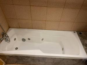 y baño con bañera blanca y pared de azulejos. en Casa Centro Dalcahue, en Dalcahue