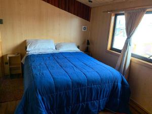 Cama azul en habitación con ventana en Casa Centro Dalcahue en Dalcahue