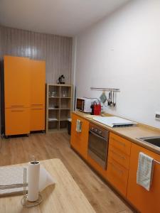 cocina con armarios de color naranja y horno con fogones en Appartamento vista Parco Adamello Brenta, en Ossana