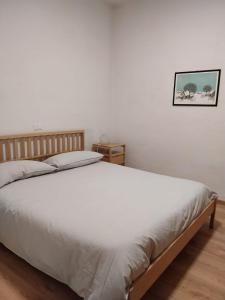 Un dormitorio con una cama blanca con una foto en la pared en Appartamento vista Parco Adamello Brenta, en Ossana