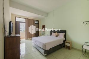 a bedroom with a bed and a television in it at Pondok Cahaya Panorama Mitra RedDoorz in Lembang