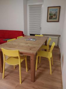 a wooden table and yellow chairs in a room at Appartamento vista Parco Adamello Brenta in Ossana