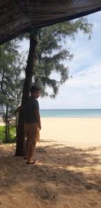 Phú LacにあるMoon homestay Phu Yenの浜辺の木の横に立つ男