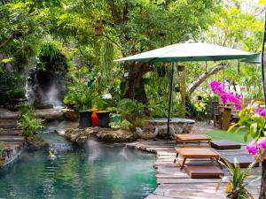 uma piscina com um guarda-sol e uma cascata em Crystal Resort Korat em Nakhon Ratchasima