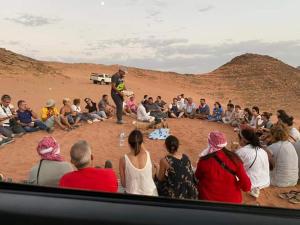 Un groupe de personnes assises dans le désert dans l'établissement Blue Camel, à Wadi Rum