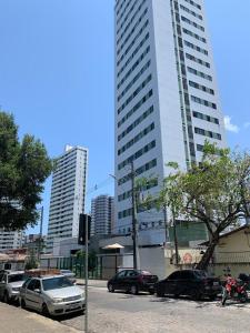 a street with cars parked in front of tall buildings at Apto moderno e bem localizado in Recife