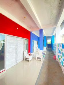 COLORFUL HOUSE في غيلي تراوانغان: غرفة بجدران حمراء وزرقاء وكراسي بيضاء