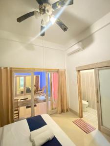 COLORFUL HOUSE في غيلي تراوانغان: غرفة نوم مع مروحة سقف وسرير