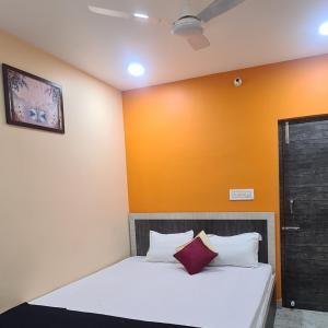 a bed in a room with an orange wall at HOTEL MANORAMA PALACE in Dhanbād