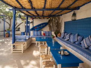 a patio with blue benches and tables and a slide at Hotel-Restaurant Le Kaouki in Sidi Kaouki