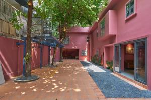 Une ruelle entre deux bâtiments roses dans l'établissement M Village Hồ Biểu Chánh, à Hô-Chi-Minh-Ville