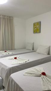 ein Zimmer mit drei Betten mit roten Bögen in der Unterkunft Mandakaru Residence Flat da Isa 01 in Porto De Galinhas