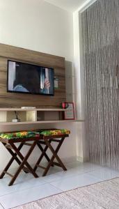 ein Wohnzimmer mit einem TV und einem Holztisch in der Unterkunft Mandakaru Residence Flat da Isa 01 in Porto De Galinhas