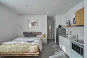 a white bedroom with a bed and a kitchen at M Village Hồ Biểu Chánh in Ho Chi Minh City