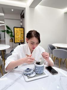 uma mulher sentada à mesa com uma chávena de chá em 婧仕女微旅 em Hou-lung-tzu