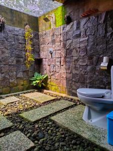 a bathroom with a toilet and a stone wall at Java Turtle Lodge Meru Betiri in Banyuwangi