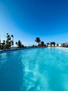 een groot zwembad van blauw water met palmbomen op de achtergrond bij Lovely Beachfront 2 bedrooms condo with 2 pools in Las Terrenas