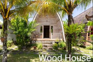 a wooden house with palm trees in front of it at Ayumar Homestay Medewi in Pulukan