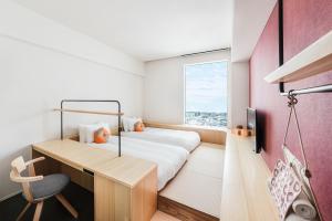 a bedroom with a bed and a desk and a window at OMO5 Kumamoto by Hoshino Resorts in Kumamoto