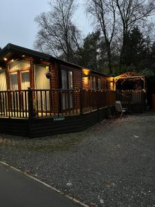 Cabaña de madera con porche y valla en Troutbeck Hot Tub Lodge 4, en Windermere