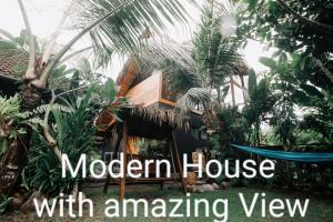 プルカンにあるAyumar Homestay Medewiのモダンな家屋で、木々や植物が植えられた素晴らしい景色を望めます。